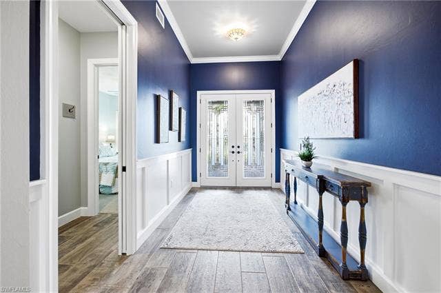 19125 Aqua Shore Dr, Estero, FL 33913 Double entry doors with decorative glass, wood-finish flooring, white wainscoting, and crown molding