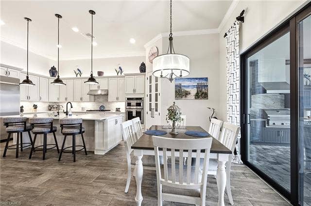 19125 Aqua Shore Dr, Estero, FL 33913 Open-concept kitchen and dining area featuring a kitchen island with seating, pendant lighting, and built-in appliances