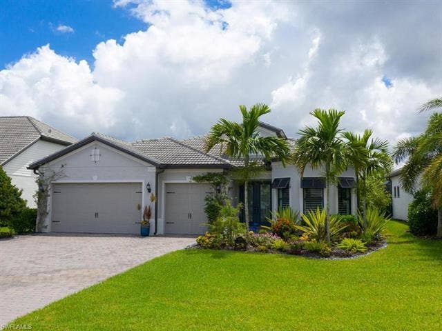 19125 Aqua Shore Dr, Estero, FL 33913 Stucco exterior with a tiled roof, 3-car garage, and a paver driveway