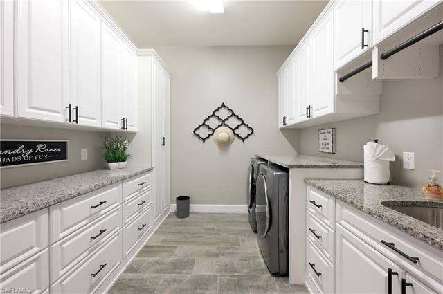 19125 Aqua Shore Dr, Estero, FL 33913 Laundry area featuring white cabinetry, granite countertops, tile flooring, and a built-in sink