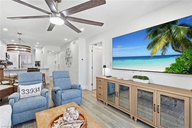 8300 Estero Blvd, #104, Fort Myers Beach, FL 33931 Open-concept living area with wood-finish flooring, recessed lighting, and a modern ceiling fan - Virtually Edited Image