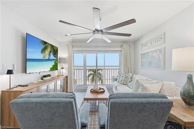 8300 Estero Blvd, #104, Fort Myers Beach, FL 33931 Sliding glass doors opening to an exterior balcony, wood-finish flooring, a contemporary ceiling fan, and built-in cabinetry - Virtually Edited Image