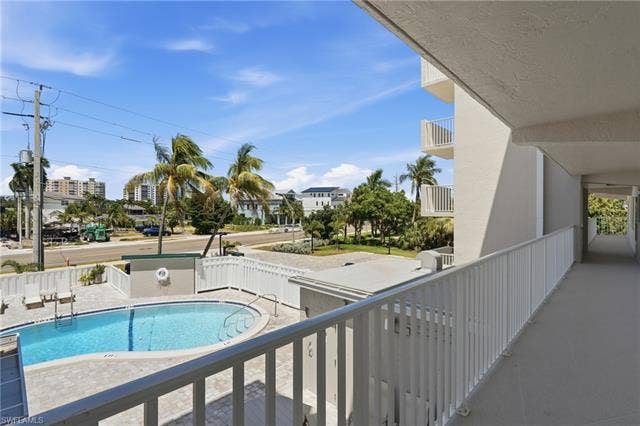 8300 Estero Blvd, #104, Fort Myers Beach, FL 33931 Exterior walkway featuring a metal railing, multiple windows, and an entry door with a brass-finish handle - Virtually Edited Image
