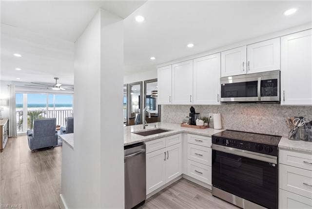 8300 Estero Blvd, #104, Fort Myers Beach, FL 33931 White cabinetry with stainless steel appliances, light-toned countertop, and wood-finish flooring - Virtually Edited Image