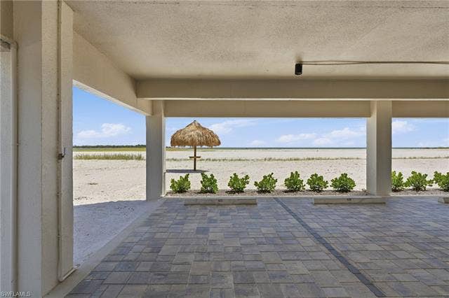 8300 Estero Blvd, #104, Fort Myers Beach, FL 33931 Covered patio with paver flooring, direct beach access, and a built-in tiki hut - Virtually Edited Image