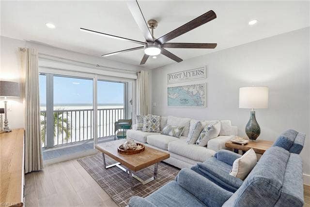 8300 Estero Blvd, #104, Fort Myers Beach, FL 33931 Large sliding glass doors opening to a balcony with metal railing, recessed ceiling lighting, and a multi-blade ceiling fan with integrated lighting - Virtually Edited Image
