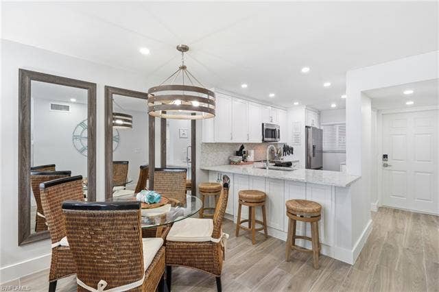 8300 Estero Blvd, #104, Fort Myers Beach, FL 33931 Contemporary kitchen featuring stainless steel appliances, white cabinetry, and granite countertops - Virtually Edited Image