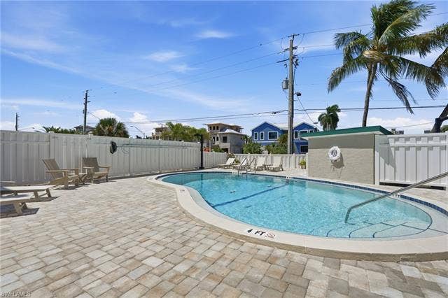 8300 Estero Blvd, #104, Fort Myers Beach, FL 33931 Outdoor pool with a paved deck, perimeter fencing, and an integrated spa - Virtually Edited Image