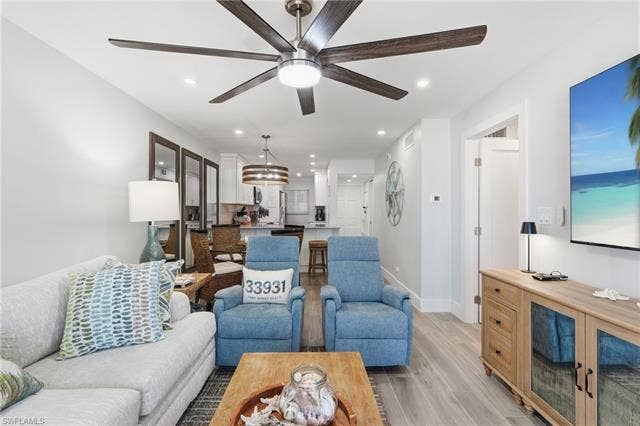 8300 Estero Blvd, #104, Fort Myers Beach, FL 33931 Open-concept living area with wood-finish flooring, recessed lighting, and a multi-blade ceiling fan - Virtually Edited Image