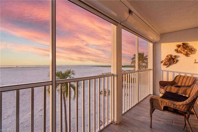 8300 Estero Blvd, #104, Fort Myers Beach, FL 33931 Screened balcony with white sand beach and ocean scenery - Virtually Edited Image
