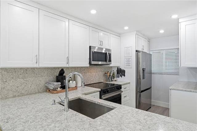 8300 Estero Blvd, #104, Fort Myers Beach, FL 33931 White shaker cabinetry, light-toned countertops, stainless steel appliances, undermount sink with gooseneck faucet, and recessed lighting - Virtually Edited Image