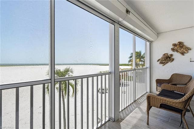 8300 Estero Blvd, #104, Fort Myers Beach, FL 33931 Screened balcony with white sand beach and ocean scenery - Virtually Edited Image