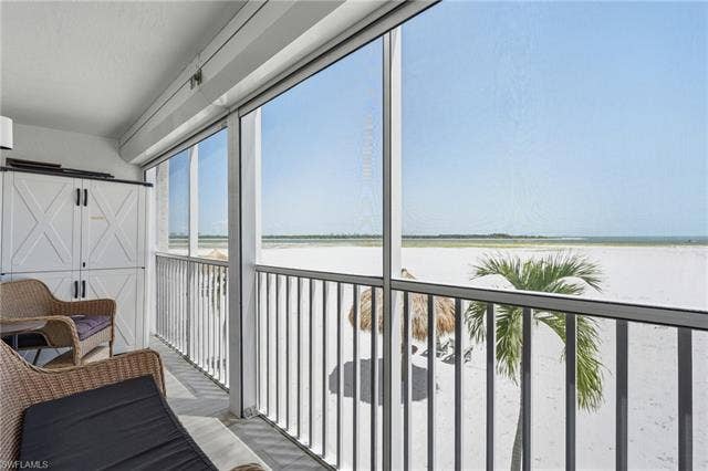 8300 Estero Blvd, #104, Fort Myers Beach, FL 33931 Screened balcony with white sand beach and ocean scenery - Virtually Edited Image