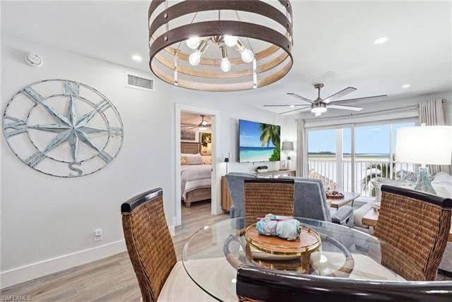 8300 Estero Blvd, #104, Fort Myers Beach, FL 33931 Open-concept living space featuring wood-finish flooring, a contemporary ceiling fan, and sliding glass doors - Virtually Edited Image
