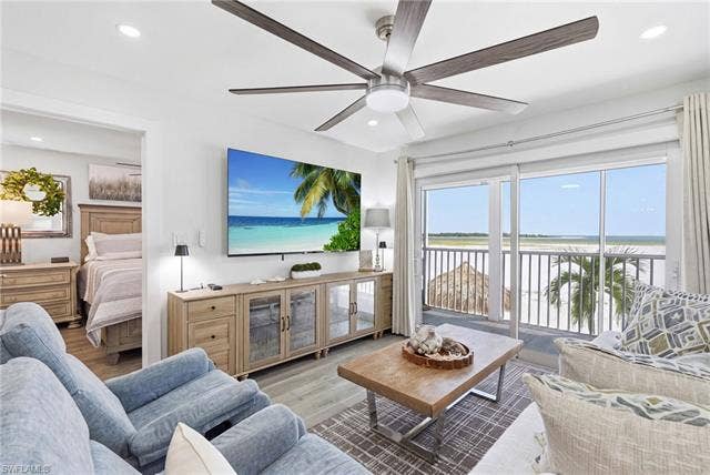 8300 Estero Blvd, #104, Fort Myers Beach, FL 33931 Sliding glass doors opening to a balcony, wood-finish flooring, recessed lighting, and a ceiling fan with integrated lighting - Virtually Edited Image