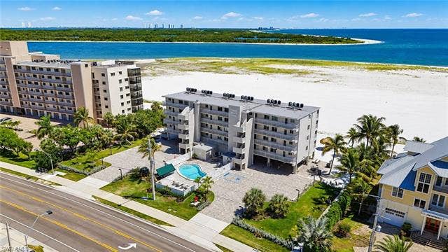 8300 Estero Blvd, #104, Fort Myers Beach, FL 33931 Beachfront multi-story building featuring a landscaped pool deck, direct beach access, and balconies - Virtually Edited Image