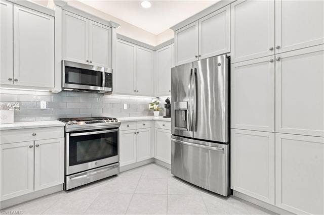 28410 Capraia Dr, Bonita Springs, FL 34135 White shaker cabinetry, stainless steel appliances, subway tile backsplash, white countertops, and recessed lighting