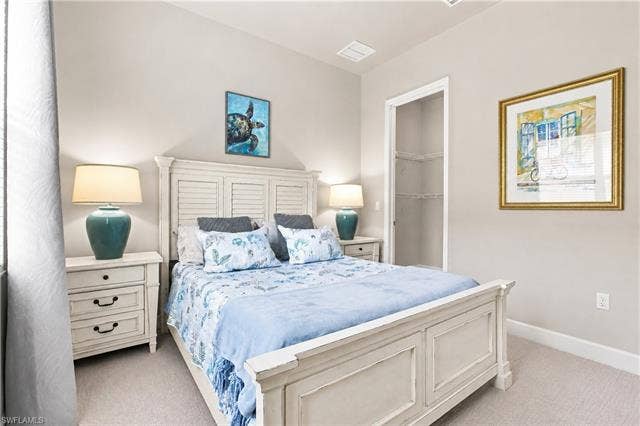 28410 Capraia Dr, Bonita Springs, FL 34135 Bright and serene primary bedroom featuring a white wooden bed frame with paneled headboard, dual nightstands with ceramic table lamps, soft carpet flooring, recessed ceiling lighting, and neutral wall finishes