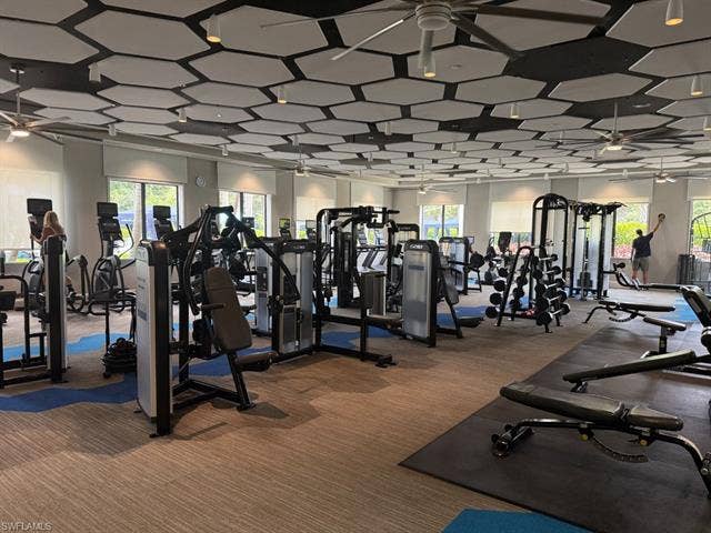 28410 Capraia Dr, Bonita Springs, FL 34135 Spacious fitness area featuring modern exercise equipment, textured ceiling panels, multiple ceiling fans, and large windows