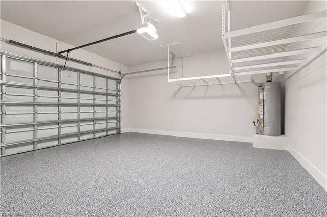 28410 Capraia Dr, Bonita Springs, FL 34135 Garage featuring epoxy flooring, overhead storage racks, a utility water heater, and an automatic garage door opener