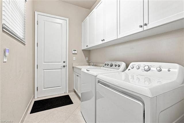 28410 Capraia Dr, Bonita Springs, FL 34135 Laundry room featuring white cabinetry, a sink with a faucet, and light-toned tile flooring