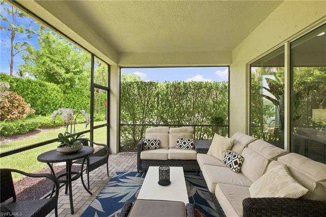28410 Capraia Dr, Bonita Springs, FL 34135 Screened patio featuring paver flooring, abundant natural light, and green landscaping