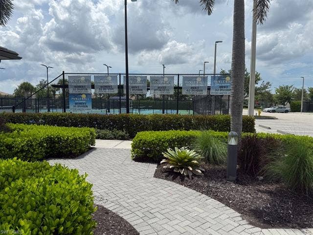 28410 Capraia Dr, Bonita Springs, FL 34135 VERY ACTIVE Tennis Programs! Paved pathway with mature landscaping, leading to pickleball courts featuring perimeter fencing and overhead lighting