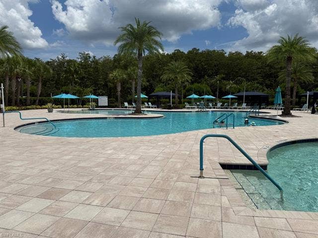 28410 Capraia Dr, Bonita Springs, FL 34135 Expansive pool deck featuring pavers, multiple swimming areas, and integrated grab rails