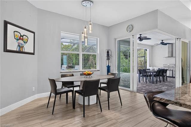 27150 Rue De Paix, Bonita Springs, FL 34135 Wood-finish flooring, contemporary chandelier, large window, and sliding glass doors leading to an outdoor kitchen area