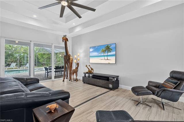 27150 Rue De Paix, Bonita Springs, FL 34135 Tray ceiling with recessed lighting and a modern ceiling fan, tile plank flooring, and sliding glass doors opening to an outdoor screened enclosure with a pool and spa