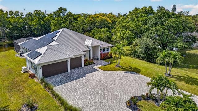 27150 Rue De Paix, Bonita Springs, FL 34135 Modern residence featuring a metal roof, solar panels, and a paver driveway