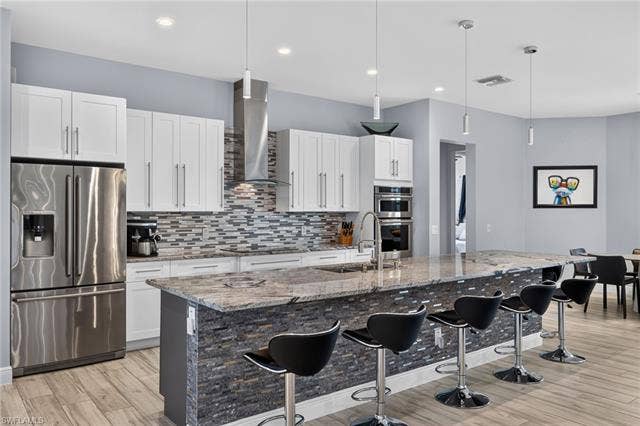 27150 Rue De Paix, Bonita Springs, FL 34135 Gourmet kitchen featuring stainless steel appliances, granite countertops, white cabinetry and decorative tile backsplash