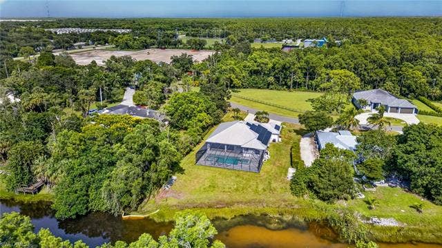 27150 Rue De Paix, Bonita Springs, FL 34135 Single-story residence with a screened pool enclosure and metal roof in the Lakes of Sans Souci neighborhood