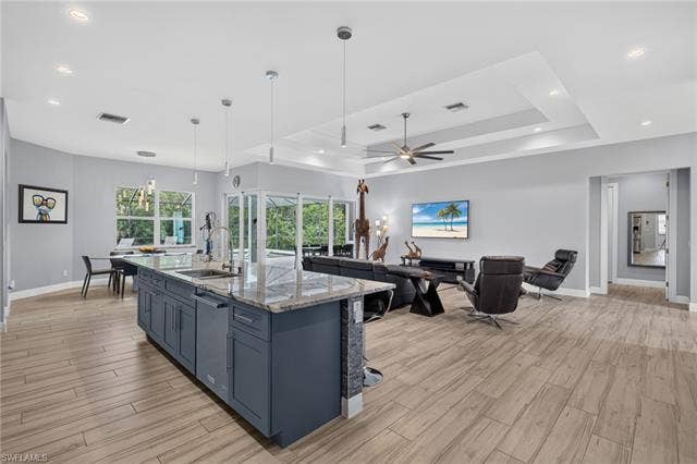 27150 Rue De Paix, Bonita Springs, FL 34135 Spacious interior with plank tile flooring, a kitchen island with granite countertops, recessed lighting, and a tray ceiling with a ceiling fan