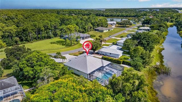 27150 Rue De Paix, Bonita Springs, FL 34135 Screened outdoor pool, water frontage, mature trees, and a metal roof