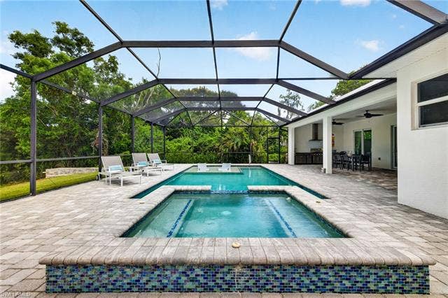 27150 Rue De Paix, Bonita Springs, FL 34135 Screened outdoor living area featuring a mosaic tile raised spa which spills over into the pool, spacious paver patio, and covered patio with outdoor kitchen