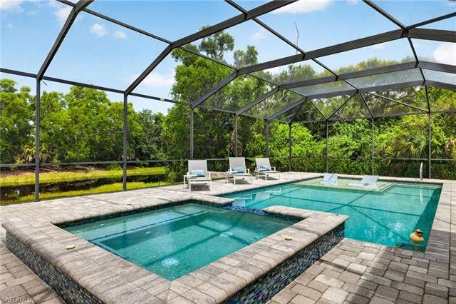 27150 Rue De Paix, Bonita Springs, FL 34135 Screened outdoor living area featuring a pool, integrated spa, paver decking and lake/canal view