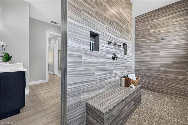 27150 Rue De Paix, Bonita Springs, FL 34135 Spacious tiled shower with multiple showerheads, recessed shelving, and an integrated bench