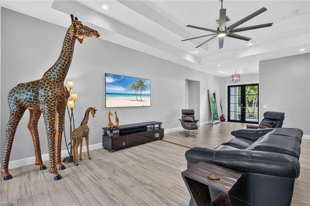 27150 Rue De Paix, Bonita Springs, FL 34135 Spacious living area featuring plank tile flooring, a tray ceiling with recessed lighting, a contemporary ceiling fan and inviting newer impact front entry doors