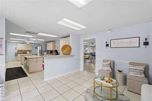 60 Palos Dr, Naples, FL 34104 Community clubhouse gathering space with an adjoining kitchen.