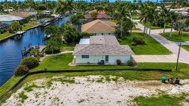 5219 S Seminole Ct, Cape Coral, FL 33904 Waterfront property with private dock, mature landscaping, and an expansive paved driveway