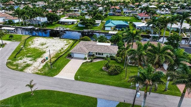 5219 S Seminole Ct, Cape Coral, FL 33904 Single-story residence with an attached garage, paved driveway, and mature landscaping
