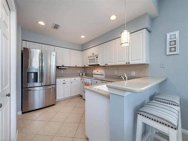 22911 Rosedale Dr, #101, Estero, FL 34135 The kitchen with breakfast bar is open to the lanai