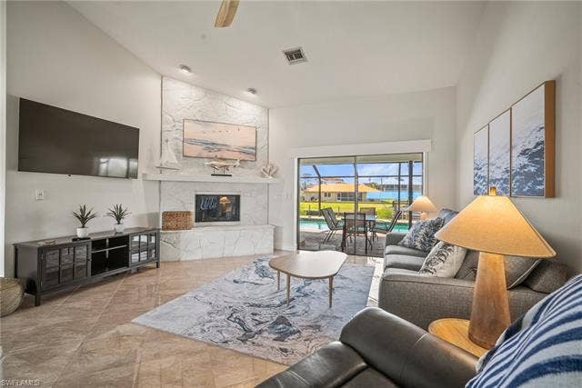 20640 Porthole Ct, Estero, FL 33928 Living area featuring a premium fireplace, visible vents, high vaulted ceiling, and ceiling fan