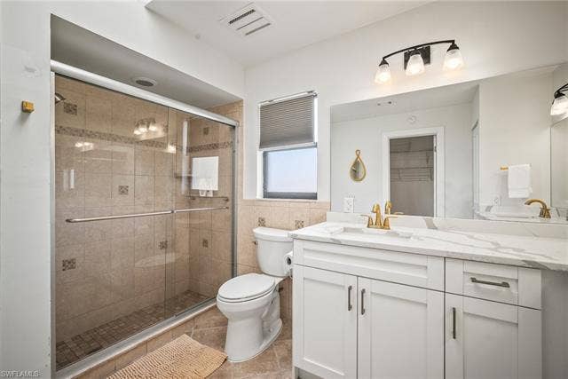 20640 Porthole Ct, Estero, FL 33928 Full bath featuring a stall shower, vanity, toilet, tile patterned flooring, and visible vents