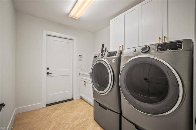 20640 Porthole Ct, Estero, FL 33928 Laundry area featuring baseboards, cabinet space, washer and clothes dryer, and light tile patterned flooring