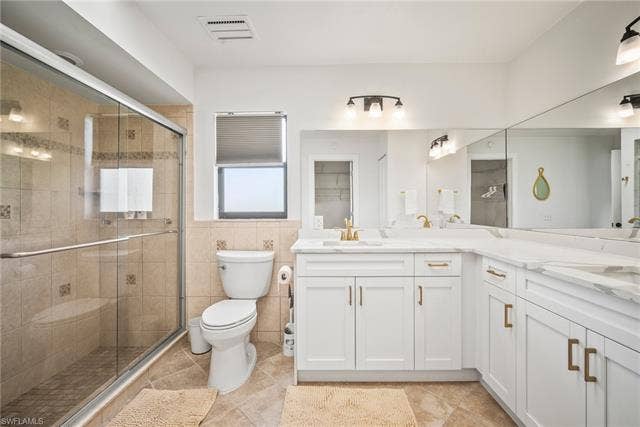 20640 Porthole Ct, Estero, FL 33928 Full bath featuring toilet, visible vents, tile patterned flooring, and a stall shower