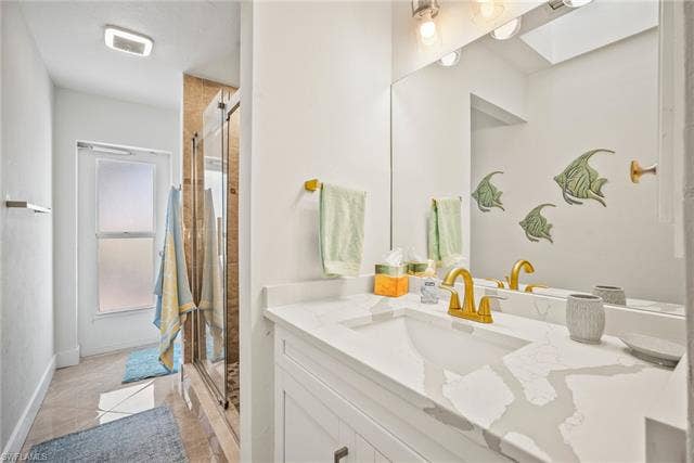 20640 Porthole Ct, Estero, FL 33928 Full bathroom with a skylight, baseboards, vanity, and a shower stall