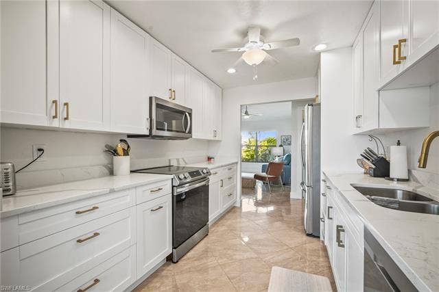 20640 Porthole Ct, Estero, FL 33928 Kitchen featuring a sink, ceiling fan, marble finish floor, stainless steel appliances, and white cabinets