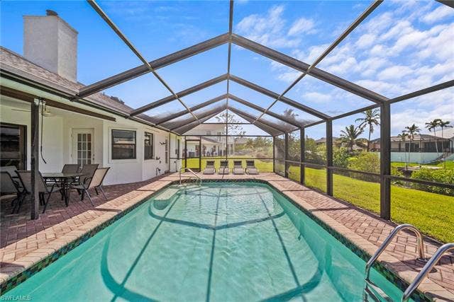 20640 Porthole Ct, Estero, FL 33928 Outdoor pool with ceiling fan, glass enclosure, a yard, and a patio